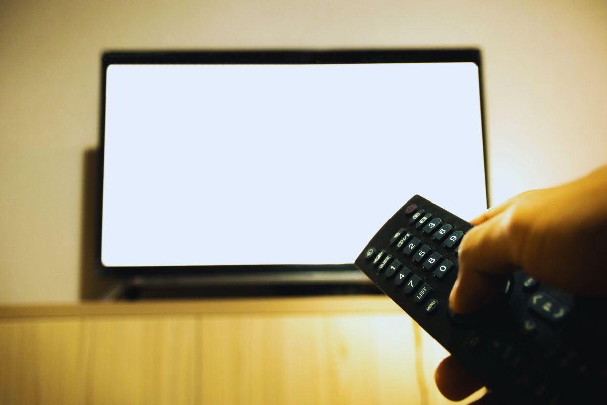 Persona che accende tv con il telecomando