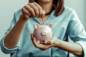 donna che mette una moneta dentro al salvadanaio